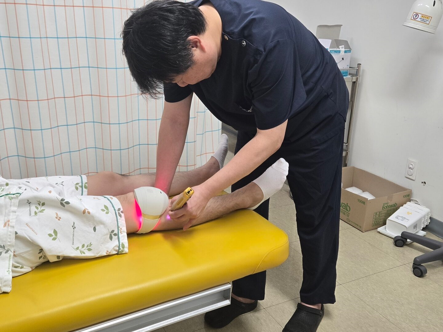 황의형 교수가 환자의 무릎에 레이저 치료기를 적용하는 모습
